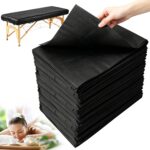 Stack of 100 black disposable massage table sheets, folded neatly, with one sheet partially unfolded on a table.