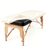 Off-white PU leather waterproof massage table cover with elastic edges, shown fitted on a massage bed.