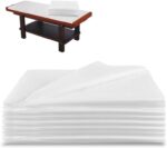 Stack of 100 white OUMETE disposable massage table sheets, unfolded to show their rectangular shape and texture.