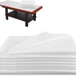 Stack of 100 white OUMETE disposable massage table sheets, unfolded to show their rectangular shape and texture.