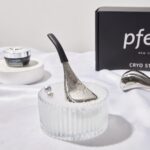 Two black pfefe cryo sticks with ergonomic handles, in a storage case, on a clean background.