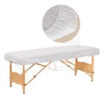 Stack of 30 white disposable fitted massage table sheets with elastic edges, on a spa table.