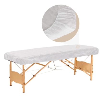 Stack of 30 white disposable fitted massage table sheets with elastic edges, on a spa table.