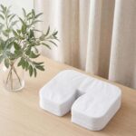 Stack of 100 Viliqiou disposable white face cradle covers for massage tables and chairs, shown unfolded and stacked.