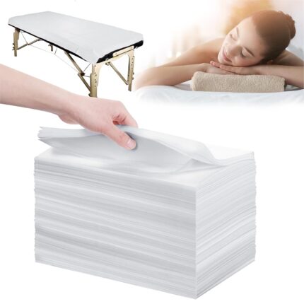 Stack of 100 white disposable non-woven bed sheets for massage tables and spa beds, neatly folded.