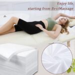 Stack of 100 white disposable non-woven bed sheets for massage tables and spa beds, neatly folded.