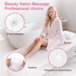 Stack of white disposable non-woven fabric massage table sheets, unfolded on a treatment bed.