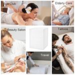 Stack of white disposable non-woven fabric massage table sheets, unfolded on a treatment bed.